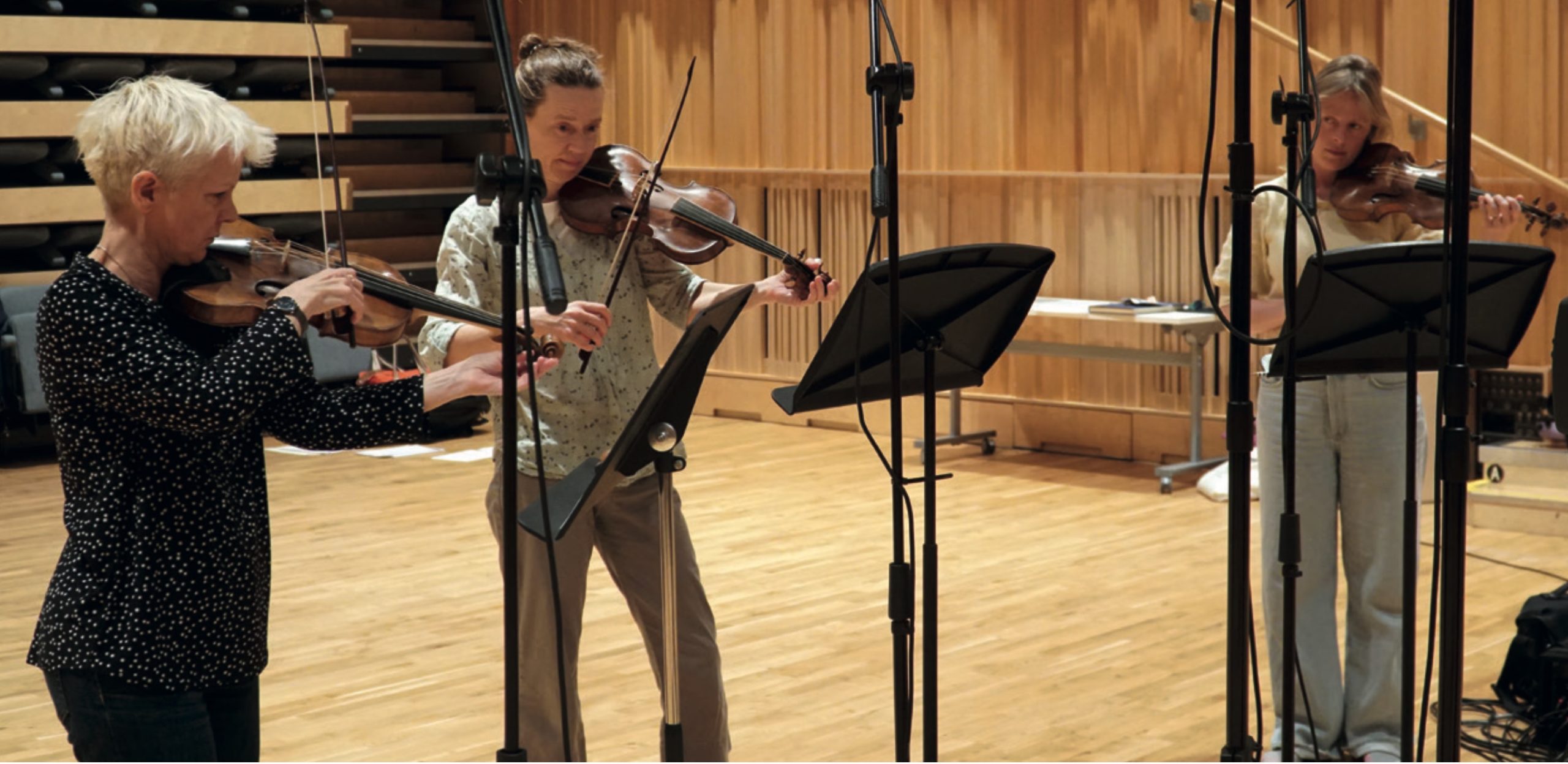 Three violinists of the Fiddlers Three playing during recording sessions